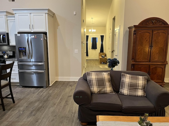 kitchen with appliances with stainless steel finishes, wood finished floors, baseboards, and white cabinets