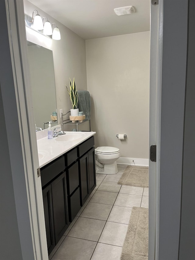 bathroom with tile patterned floors, toilet, and double vanity