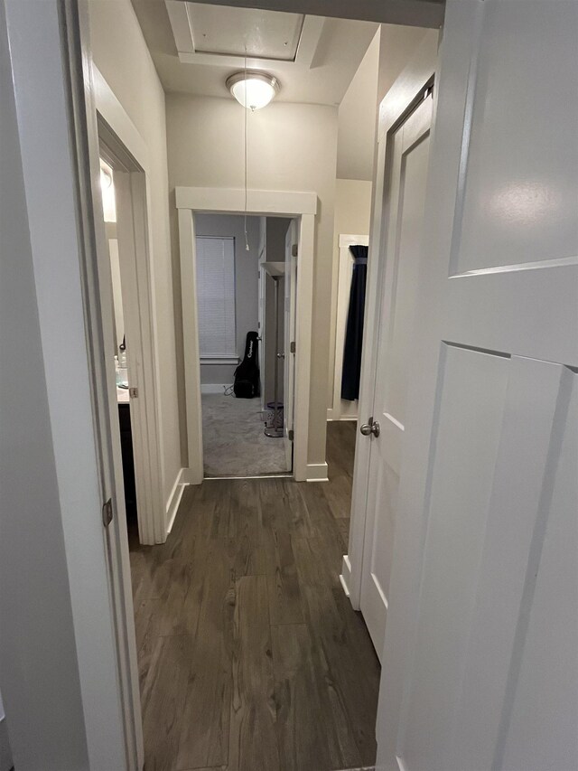 hallway featuring attic access, dark wood-style flooring, and baseboards