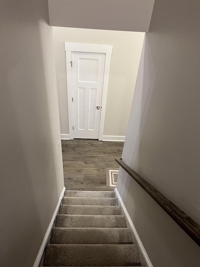 staircase featuring wood finished floors and baseboards