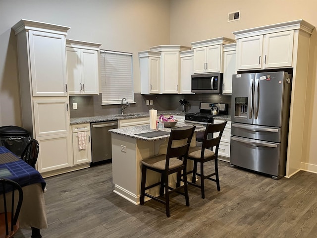 kitchen with stainless steel appliances, a sink, tasteful backsplash, a center island, and a high ceiling