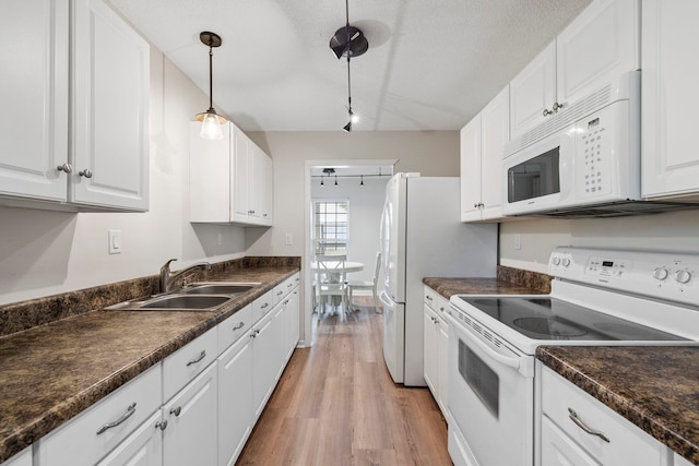 kitchen featuring white appliances, dark countertops, a sink, white cabinetry, and a textured ceiling