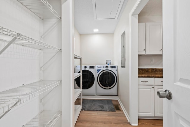 clothes washing area featuring washer and clothes dryer, light wood-type flooring, attic access, and electric panel