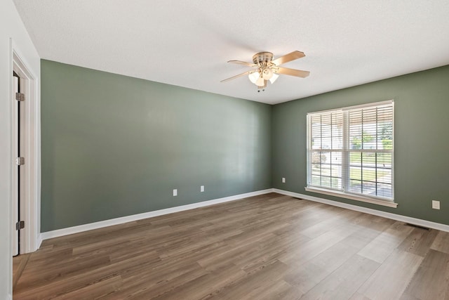 spare room with a ceiling fan, wood finished floors, and baseboards