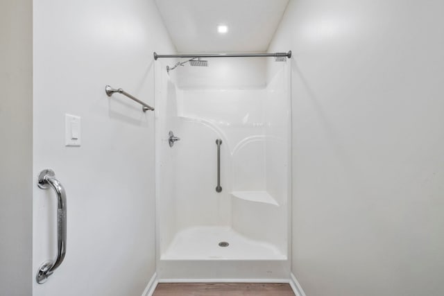bathroom featuring a shower, wood finished floors, and baseboards