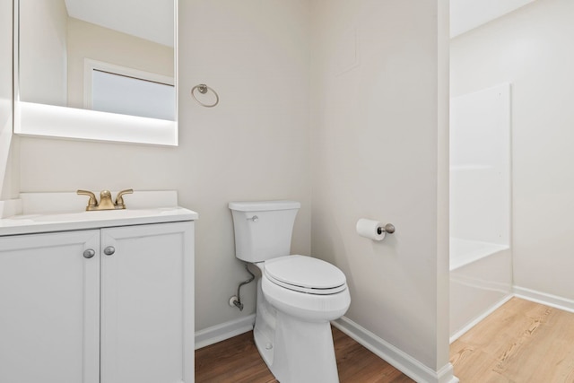 full bath featuring wood finished floors, toilet, vanity, baseboards, and a tub