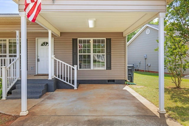 view of exterior entry with crawl space, a yard, and covered porch