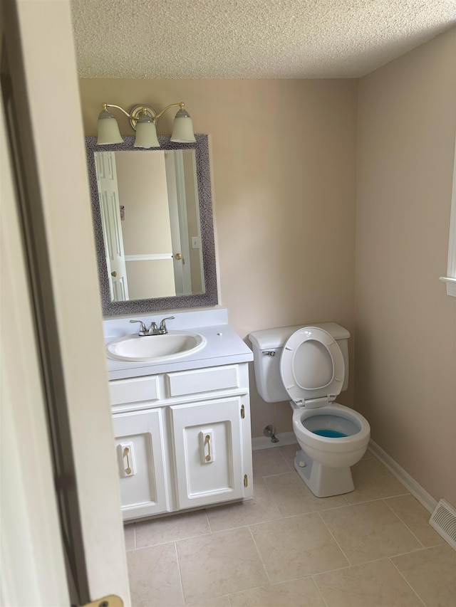 bathroom with toilet, tile patterned flooring, a textured ceiling, baseboards, and vanity