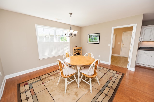 dining area featuring a chandelier, light wood-style flooring, and baseboards