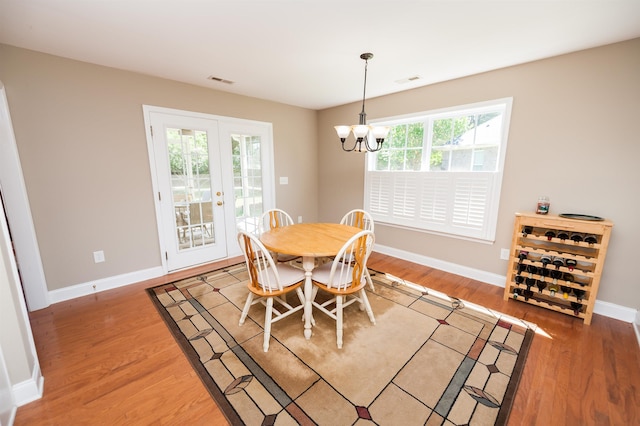 dining space with light wood-style floors, a chandelier, and baseboards