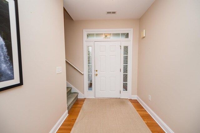 foyer featuring light wood-style flooring, stairway, and baseboards
