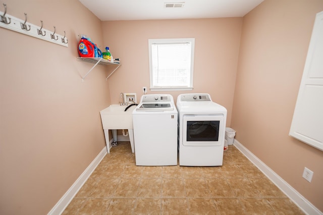 clothes washing area featuring washer and dryer, light tile patterned floors, and baseboards