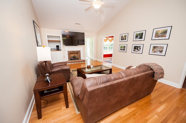 living area featuring a ceiling fan, light wood finished floors, baseboards, and high vaulted ceiling