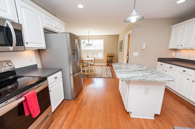 kitchen with appliances with stainless steel finishes, light wood-style flooring, a chandelier, a center island, and white cabinetry