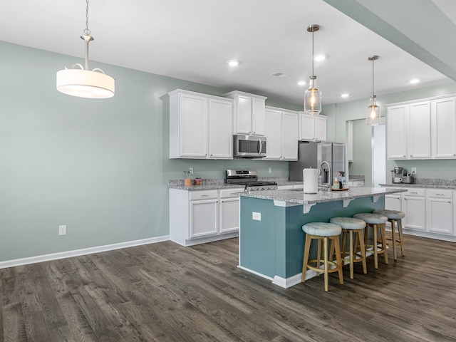 kitchen featuring appliances with stainless steel finishes, dark wood-type flooring, white cabinetry, recessed lighting, and a center island with sink
