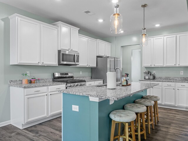 kitchen featuring appliances with stainless steel finishes, a sink, a kitchen bar, white cabinets, and recessed lighting