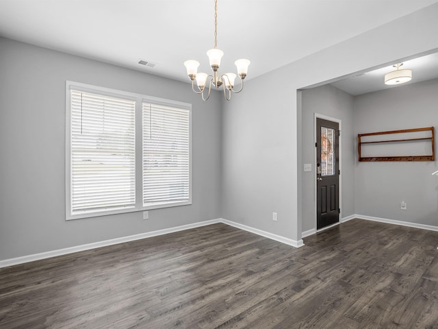 unfurnished room featuring healthy amount of natural light, a chandelier, dark wood finished floors, and baseboards