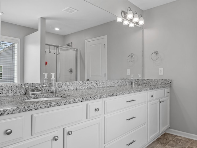 bathroom featuring a shower stall, baseboards, and double vanity