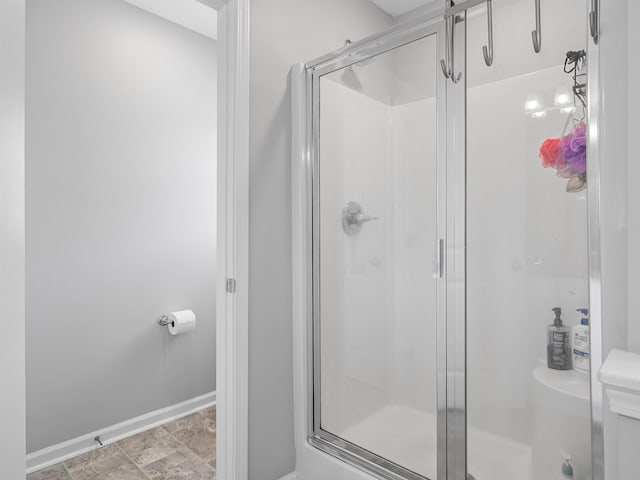 bathroom with baseboards, a stall shower, and toilet