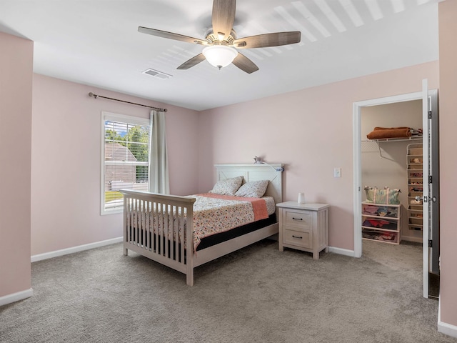 bedroom featuring light carpet, a spacious closet, baseboards, ceiling fan, and a closet