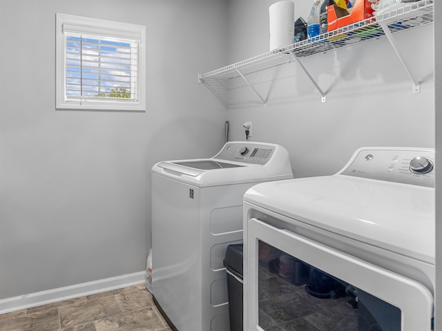 laundry room featuring independent washer and dryer, baseboards, and stone finish flooring