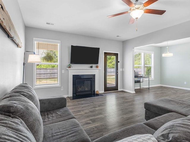 living area featuring ceiling fan, wood finished floors, a fireplace with flush hearth, and baseboards