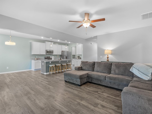 living room with ceiling fan, wood finished floors, and baseboards