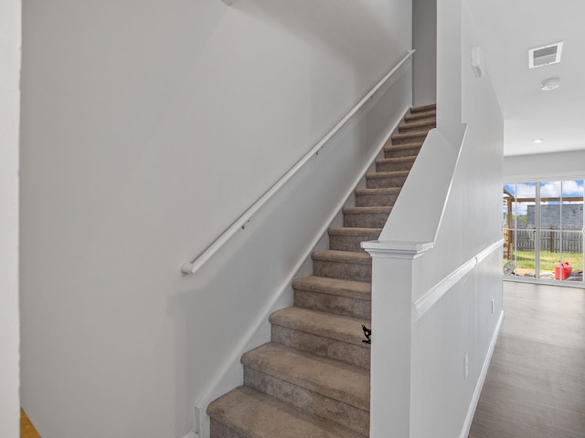 stairway with wood finished floors and recessed lighting