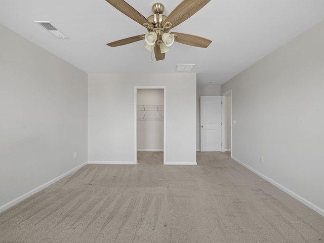unfurnished bedroom with baseboards, light carpet, a spacious closet, and a closet