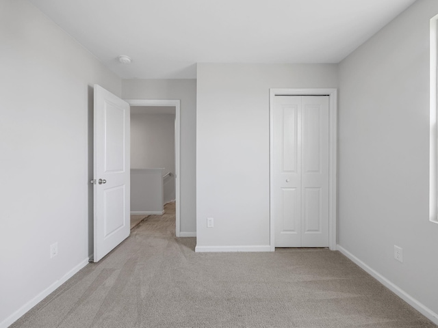 unfurnished bedroom with carpet flooring, a closet, and baseboards
