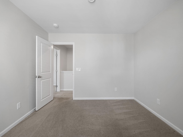 unfurnished room with carpet flooring and baseboards