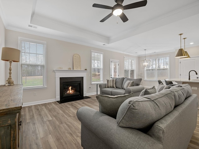 living area with light wood-style flooring, healthy amount of natural light, crown molding, and recessed lighting