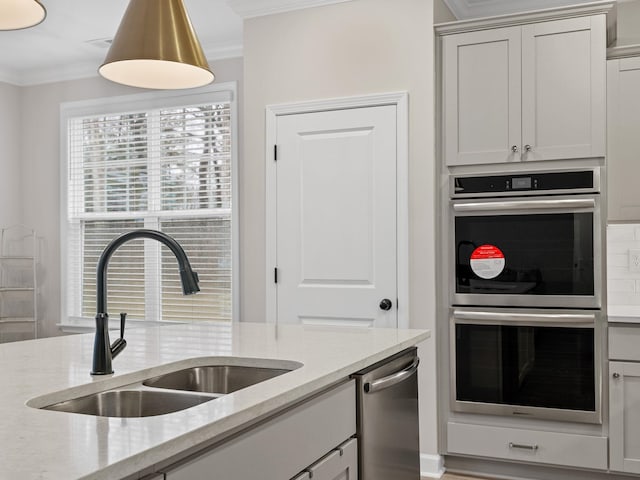 kitchen with appliances with stainless steel finishes, ornamental molding, a sink, and light stone counters