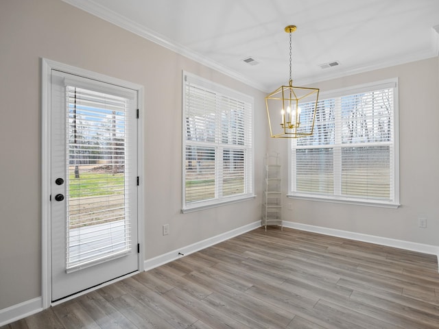 unfurnished dining area featuring a chandelier, ornamental molding, wood finished floors, healthy amount of natural light, and baseboards