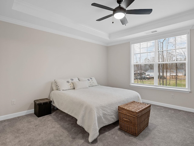 carpeted bedroom with a raised ceiling, crown molding, baseboards, and ceiling fan