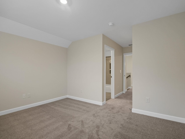 carpeted spare room with baseboards, a smoke detector, and vaulted ceiling