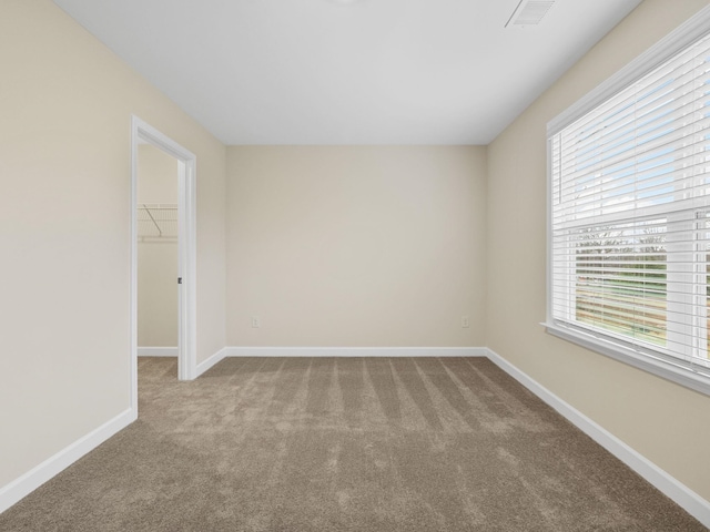 carpeted spare room featuring healthy amount of natural light and baseboards