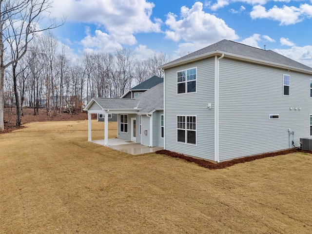 rear view of property featuring a patio, a yard, a shingled roof, and cooling unit