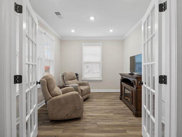 living area with french doors, crown molding, baseboards, wood finished floors, and recessed lighting