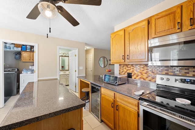 kitchen featuring stainless steel appliances, independent washer and dryer, wine cooler, backsplash, and ceiling fan