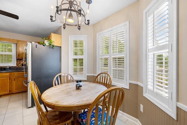 dining room with a chandelier, a wainscoted wall, and light tile patterned floors