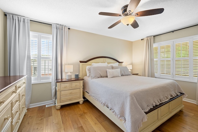 bedroom featuring multiple windows, light wood-style floors, baseboards, and ceiling fan