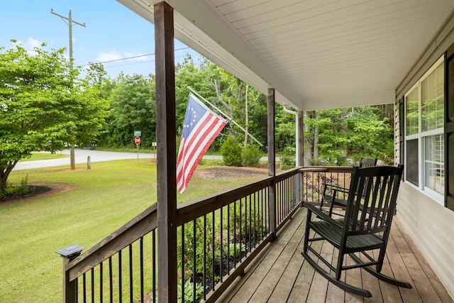 wooden terrace featuring a porch and a lawn