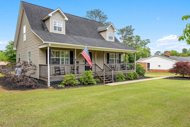 new england style home with a front yard, a porch, and a shingled roof