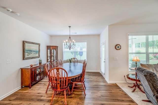 dining room with a chandelier, light wood-type flooring, and baseboards