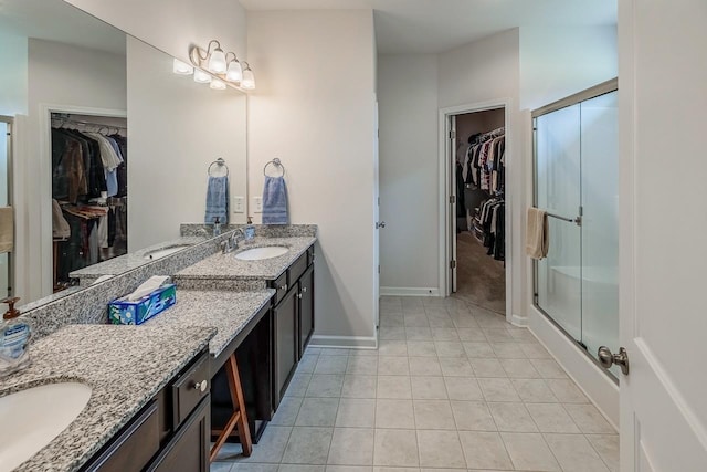 full bath with vanity, a stall shower, tile patterned flooring, baseboards, and a walk in closet