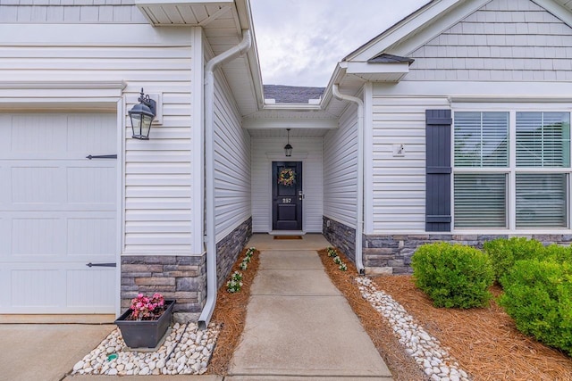 view of exterior entry with stone siding and a garage