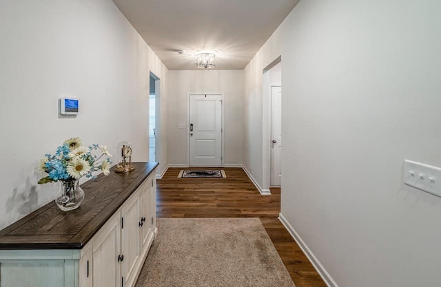 doorway to outside with dark wood-type flooring and baseboards