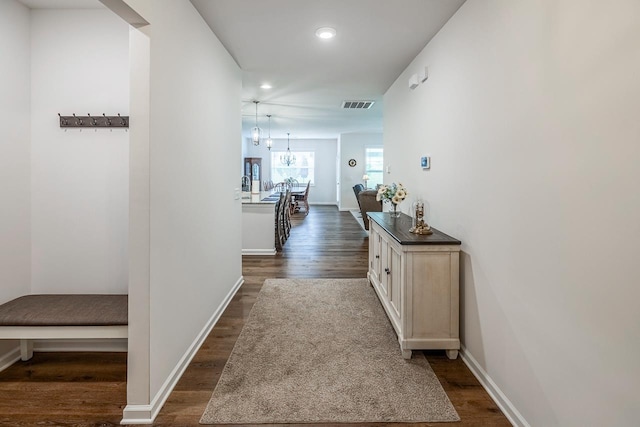 corridor with dark wood-style floors, recessed lighting, a chandelier, and baseboards