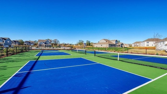 view of tennis court featuring a residential view and fence